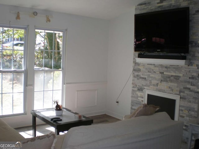 unfurnished bedroom with multiple windows, a stone fireplace, and wood finished floors