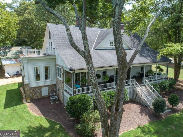 back of house with roof with shingles, a chimney, stairway, central AC unit, and stone siding