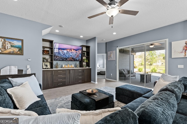 living area with a ceiling fan, recessed lighting, light wood-style flooring, and a textured ceiling