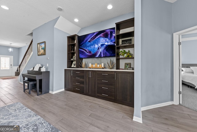 bar with wood tiled floor, baseboards, stairway, and a textured ceiling