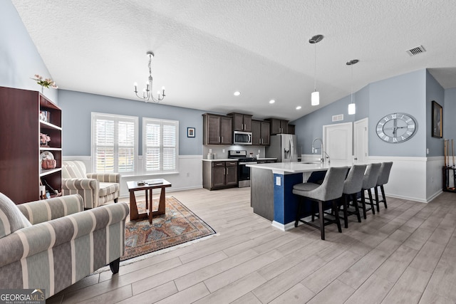 kitchen featuring light wood finished floors, visible vents, a breakfast bar, stainless steel appliances, and light countertops