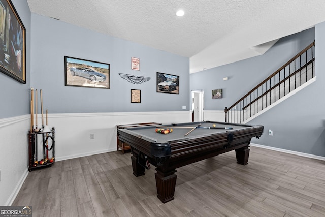 game room featuring a textured ceiling, pool table, wood finished floors, and baseboards