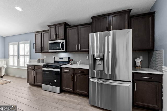 kitchen featuring appliances with stainless steel finishes, light countertops, dark brown cabinetry, and decorative backsplash