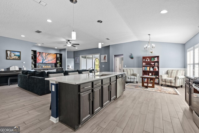 kitchen with light wood finished floors, light countertops, appliances with stainless steel finishes, open floor plan, and a sink