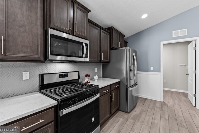 kitchen with lofted ceiling, stainless steel appliances, visible vents, and dark brown cabinetry