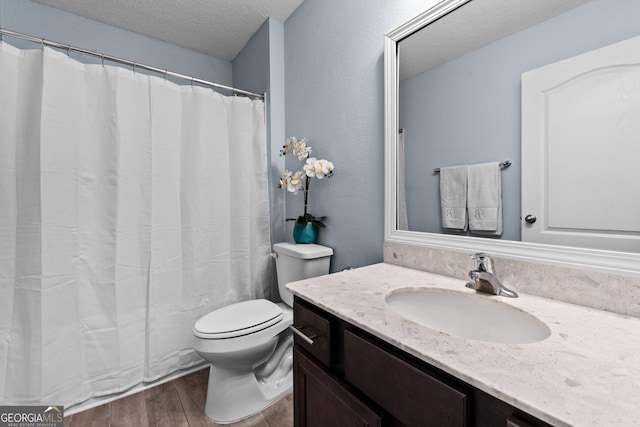 bathroom with vanity, a textured ceiling, toilet, and wood finished floors