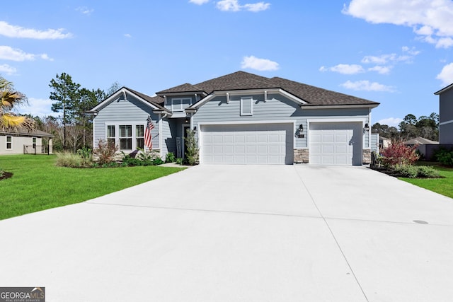 view of front of home with a shingled roof, a front yard, a garage, stone siding, and driveway