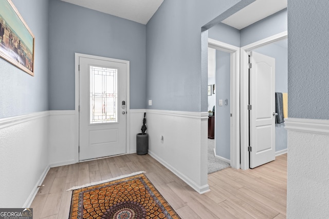 doorway to outside featuring light wood-style floors, baseboards, and a textured wall