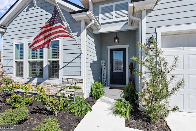 doorway to property featuring a garage and stone siding