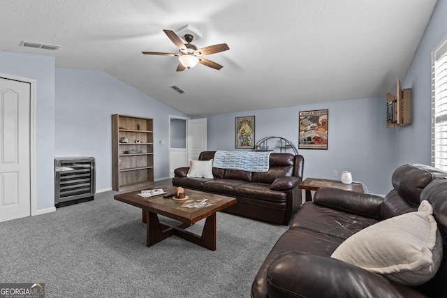 carpeted living room with beverage cooler, vaulted ceiling, visible vents, and a ceiling fan