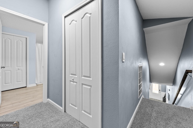 hallway with a textured wall, carpet flooring, and baseboards