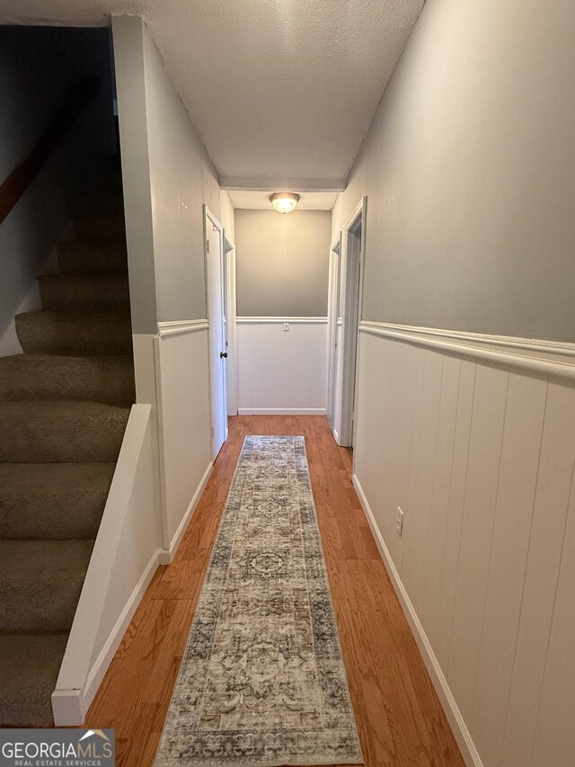 312 Schuman Dr, Bloomingdale, GA 31302 - hall with light wood-type flooring, stairs, wainscoting, and a textured ceiling