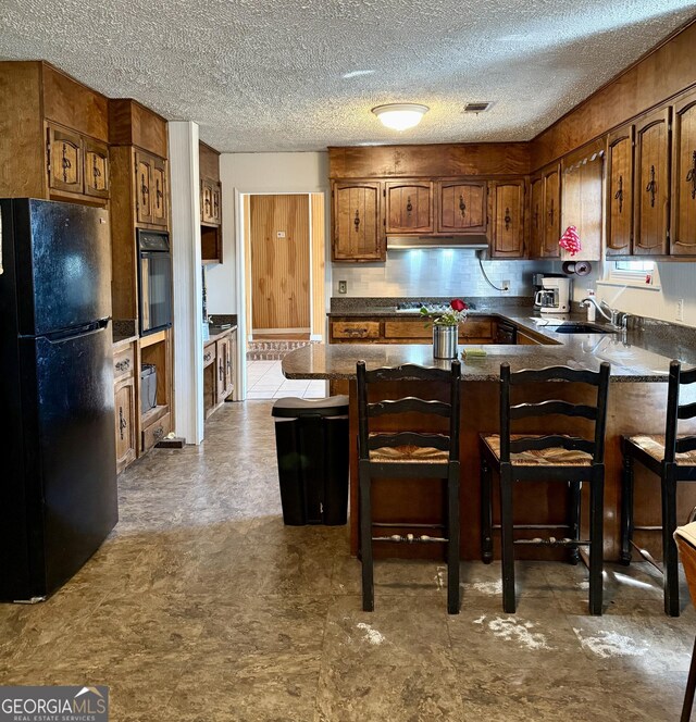 312 Schuman Dr, Bloomingdale, GA 31302 - kitchen with black appliances, a peninsula, dark countertops, a sink, and under cabinet range hood