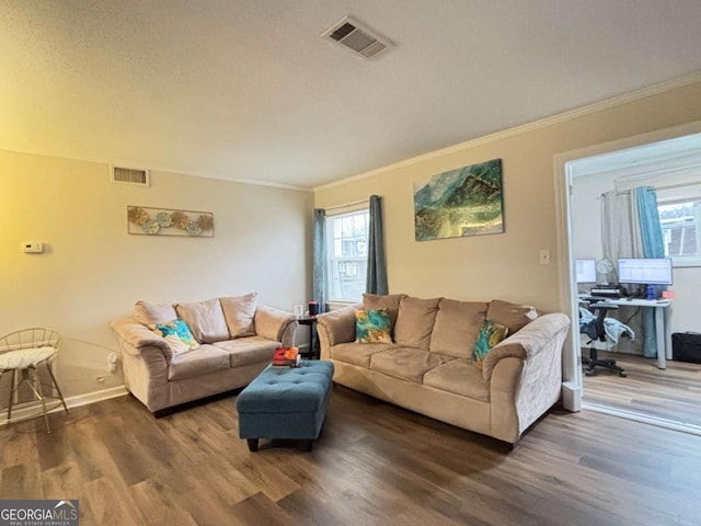 living room featuring dark wood-style floors, ornamental molding, and visible vents