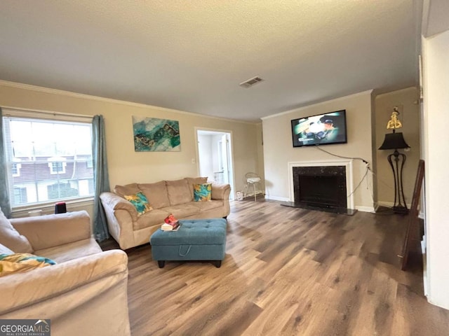 living area featuring crown molding, visible vents, a fireplace, and wood finished floors