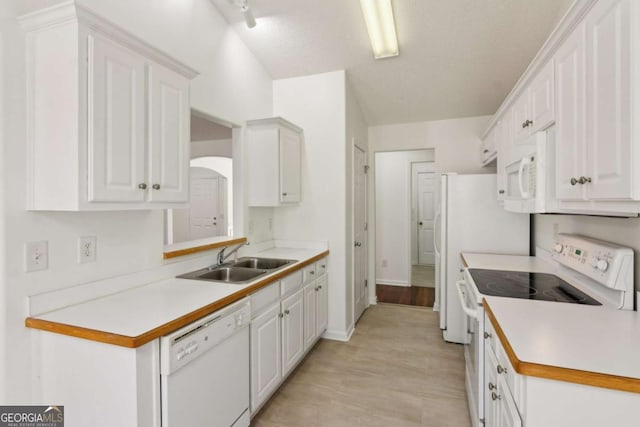 kitchen with white appliances, light countertops, a sink, and white cabinets