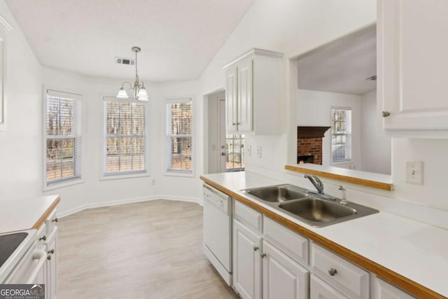 kitchen featuring white appliances, visible vents, white cabinets, light countertops, and a sink