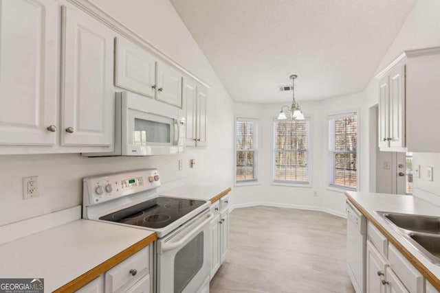 kitchen with light countertops, white appliances, decorative light fixtures, and white cabinets