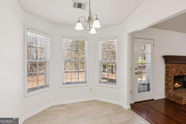 unfurnished dining area featuring plenty of natural light, a fireplace, visible vents, and baseboards