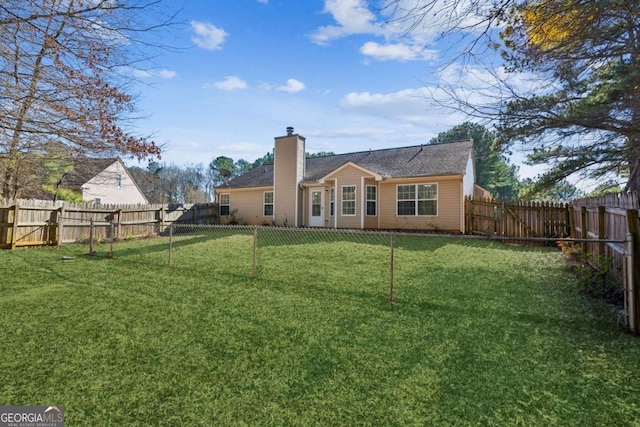 rear view of house featuring a yard, a chimney, and a fenced backyard