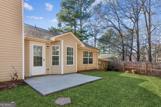 exterior space with roof with shingles, a lawn, a patio area, and fence