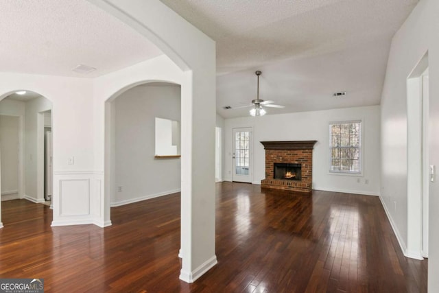 unfurnished living room with visible vents, ceiling fan, dark wood-type flooring, a textured ceiling, and a fireplace