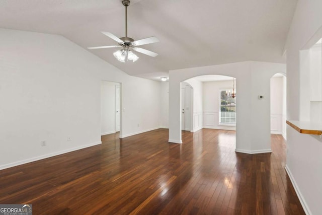 unfurnished living room with arched walkways, lofted ceiling, dark wood-style flooring, a ceiling fan, and baseboards