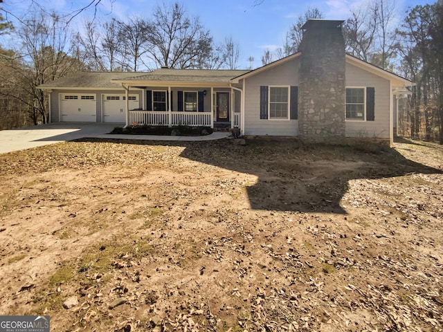 ranch-style home featuring an attached garage, a chimney, a porch, and concrete driveway