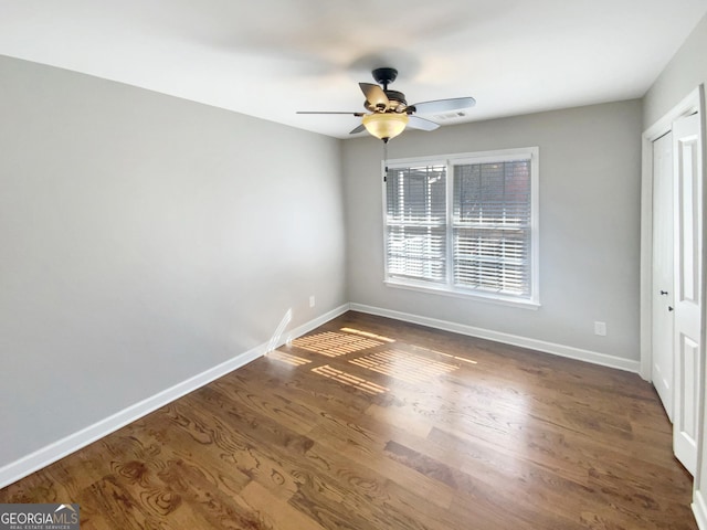 unfurnished bedroom with ceiling fan, dark wood-style flooring, visible vents, and baseboards