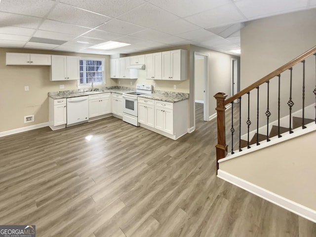 kitchen with white appliances, wood finished floors, and white cabinets