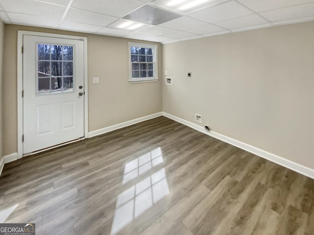 interior space featuring wood finished floors, a paneled ceiling, and baseboards