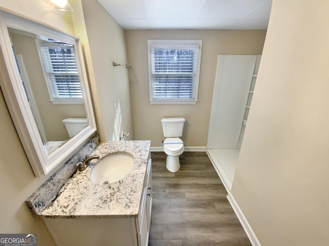 bathroom with toilet, baseboards, wood finished floors, and vanity