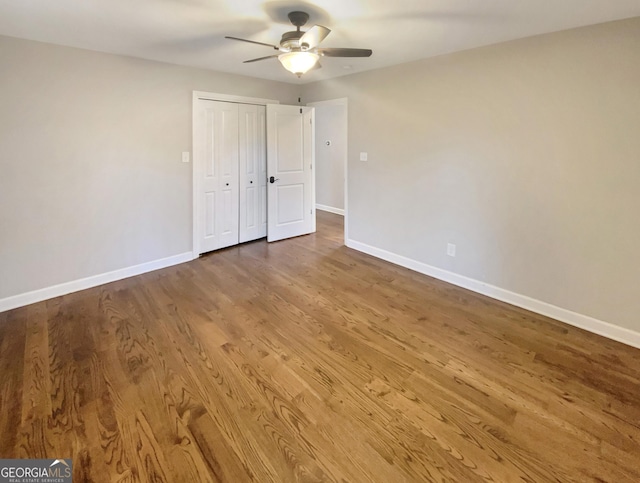 unfurnished bedroom with ceiling fan, a closet, wood finished floors, and baseboards