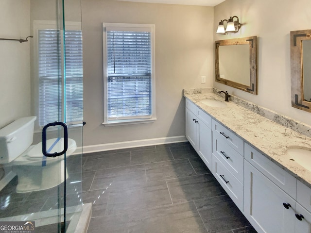 full bathroom with double vanity, a shower stall, baseboards, and a sink