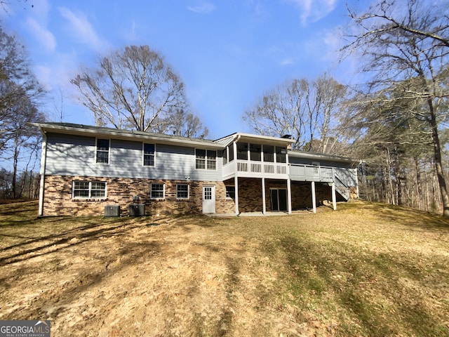 rear view of property with a sunroom, stairway, central AC unit, and a yard