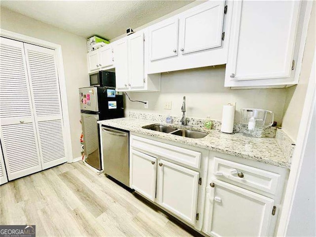 kitchen featuring black microwave, white cabinets, a sink, and dishwasher