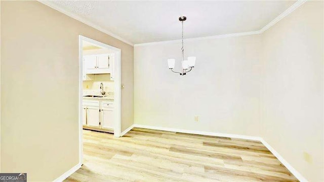 unfurnished dining area featuring ornamental molding, light wood finished floors, a sink, and baseboards