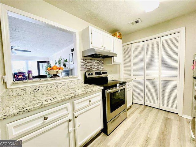 kitchen with visible vents, white cabinets, stainless steel electric range oven, light wood-style flooring, and under cabinet range hood