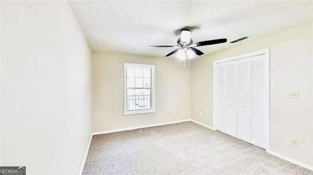 unfurnished bedroom with a textured ceiling, a closet, light carpet, and visible vents