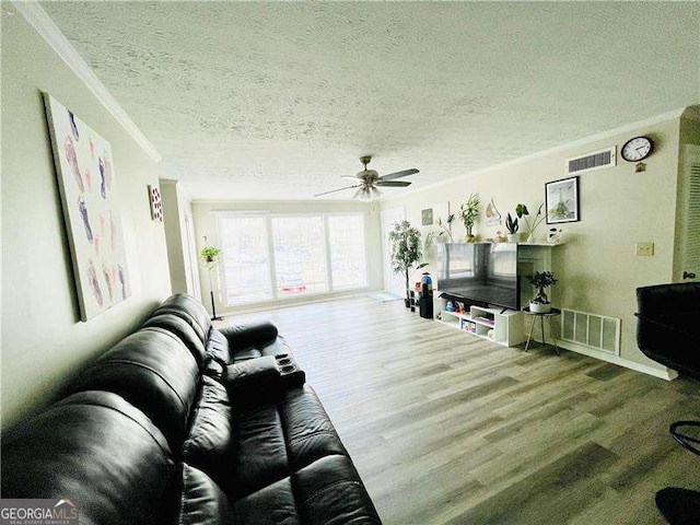 living room featuring crown molding, a textured ceiling, visible vents, and wood finished floors