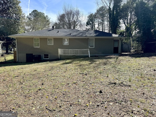 back of property with brick siding and a yard