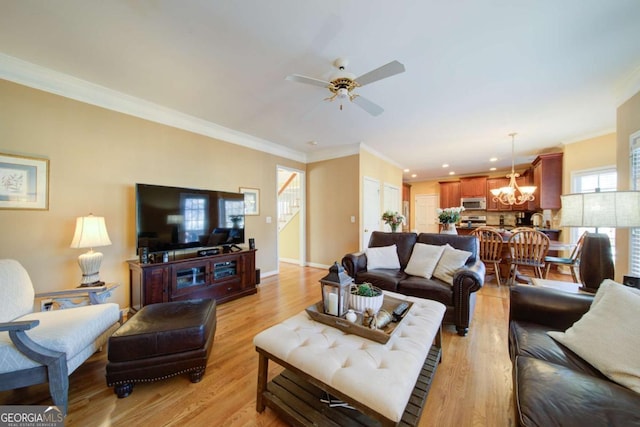 living area featuring ornamental molding, baseboards, light wood finished floors, and ceiling fan with notable chandelier