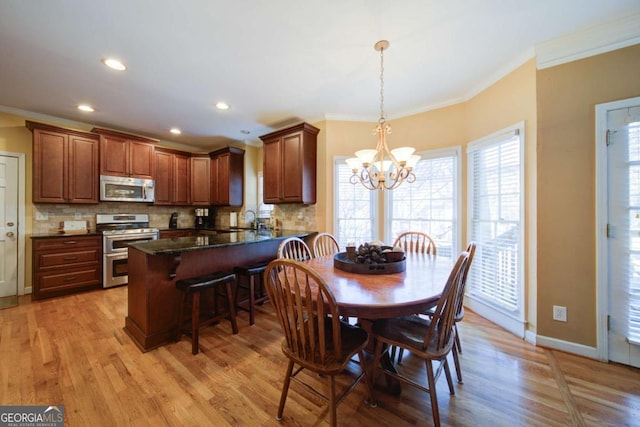 dining space with light wood-style floors, a notable chandelier, baseboards, and crown molding