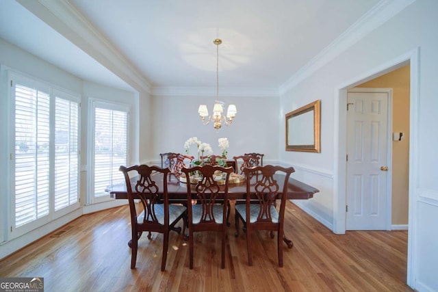 dining room featuring light wood-type flooring, crown molding, baseboards, and a notable chandelier