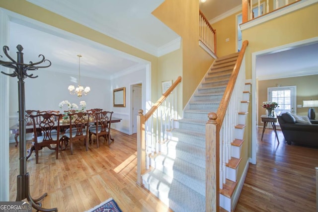 stairs featuring a chandelier, ornamental molding, wood finished floors, and baseboards