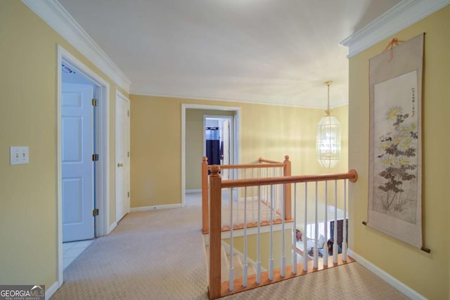 hall with baseboards, ornamental molding, carpet flooring, an upstairs landing, and a chandelier