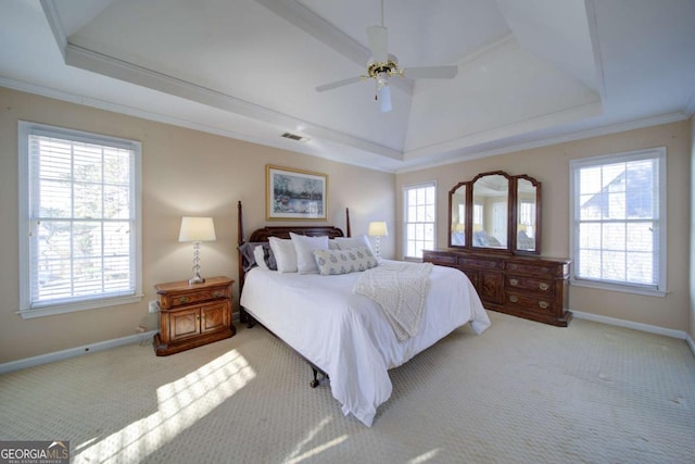 carpeted bedroom with baseboards, multiple windows, ornamental molding, and a raised ceiling