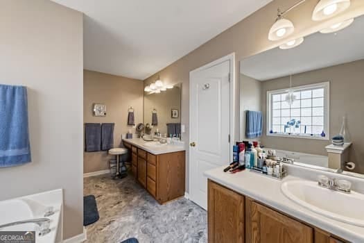 bathroom featuring two vanities, a garden tub, and a sink