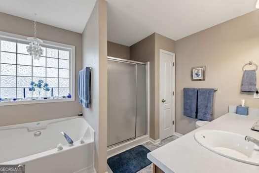 full bath with a chandelier, a stall shower, a garden tub, and vanity