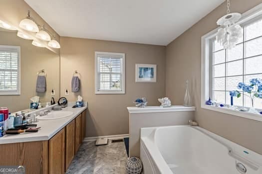 full bathroom featuring a garden tub, a wealth of natural light, and vanity